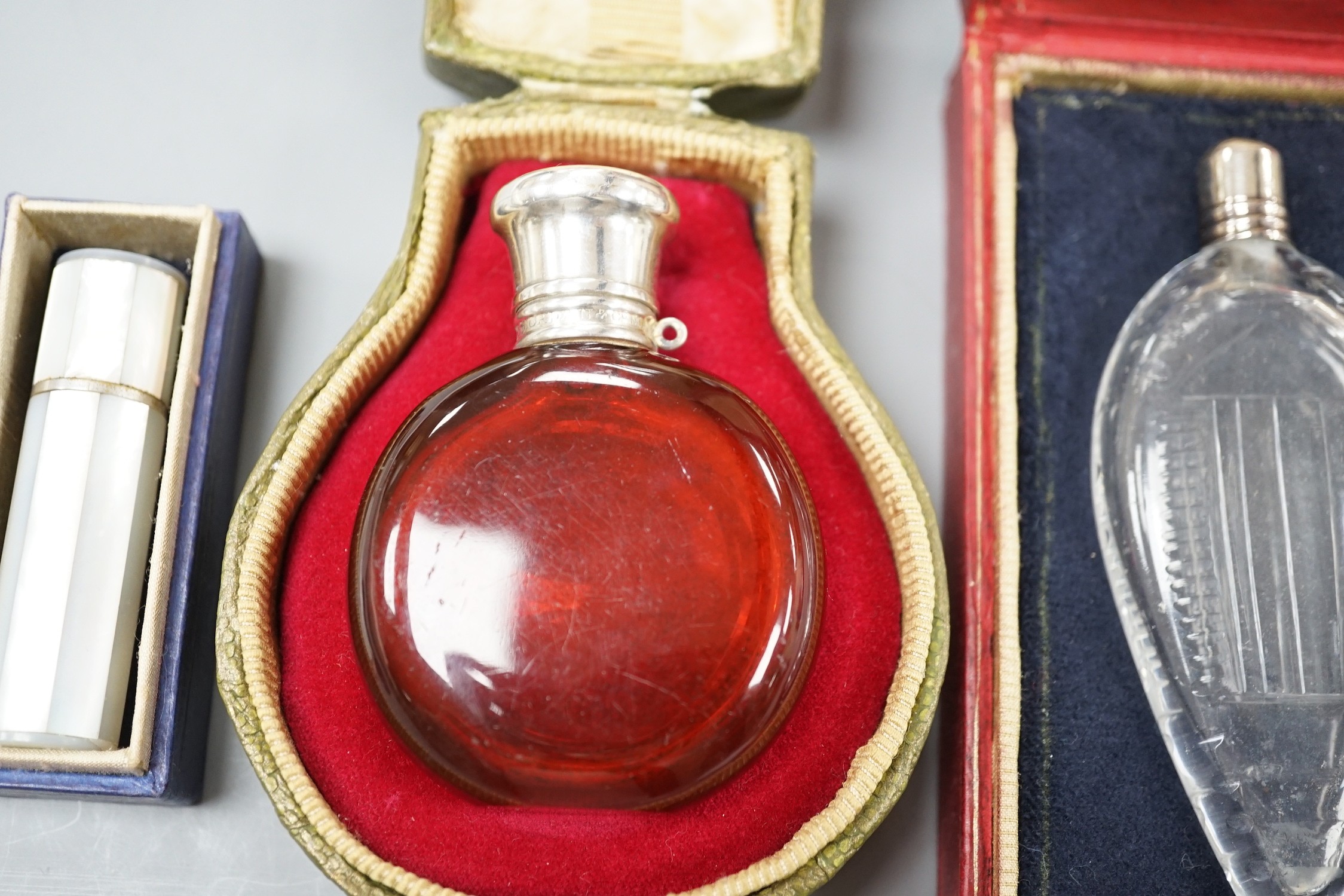 A cased Sampson Mordan white metal mounted ruby glass scent bottle, 7cm, one other mounted glass scent bottle and a mother of pearl mounted lipstick holder.